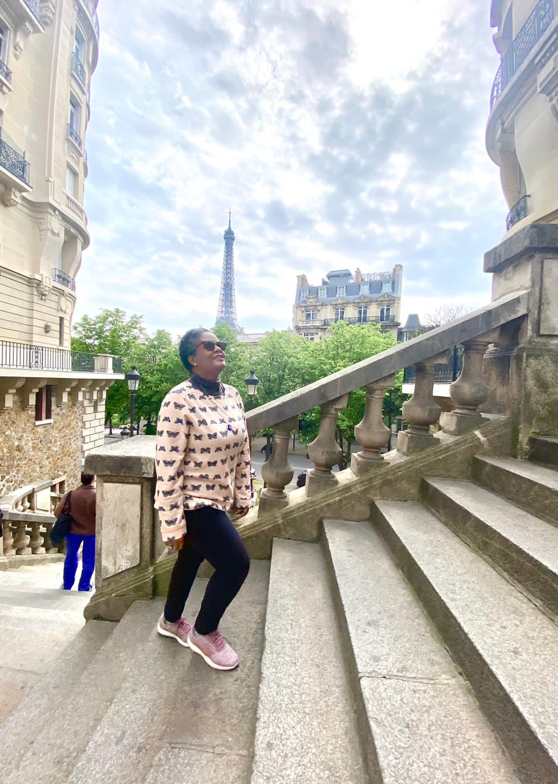 Flavia numa escadaria de Paris com a Torre Eiffel ao fundo